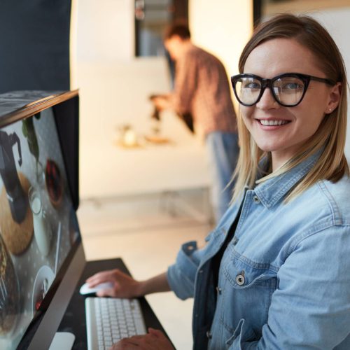 Young food-designer or blogger sitting in front of computer in studio